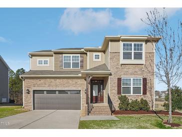 Charming two-story home with stone and siding exterior, a covered porch, and attached two-car garage at 644 Hiddenbrook Dr, Durham, NC 27703