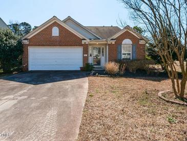 Charming single-story brick home featuring an attached garage and well-maintained front yard at 101 Tiverton Woods Dr, Holly Springs, NC 27540