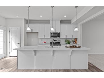Bright kitchen featuring a large island, pendant lighting, and white cabinetry at 1329 Channing Park Cir, Cary, NC 27519