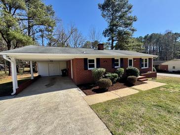 Charming red brick home with well-manicured lawn, complemented by a convenient carport and black shutters at 1723 Lynne Ave, Henderson, NC 27536