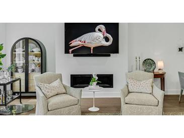 Elegant living room features fireplace with flamingo art above, two chairs, and curated decor at 4007 Southpoint Landing Way, Durham, NC 27707