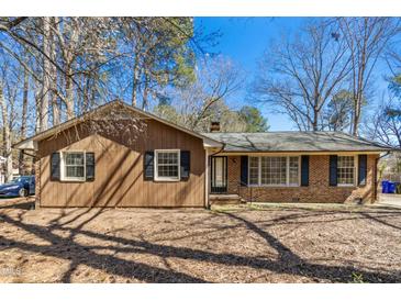 Inviting one-story home featuring a brick and wood facade, surrounded by mature trees and a well-maintained yard at 411 Colony Woods Dr, Chapel Hill, NC 27517