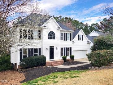 Charming two-story white home with a black roof, blooming trees, and manicured landscaping at 725 Littleleaf Ct, Holly Springs, NC 27540