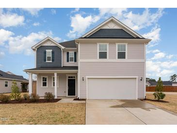 Charming two-story home with vinyl siding, garage and manicured front lawn at 1077 Kafka Dr, Fuquay Varina, NC 27526