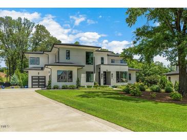 Beautiful modern home with lush green lawn and a long driveway leading to a two-car garage at 132 Edward Booth Ln, Durham, NC 27713