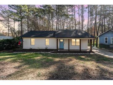 Charming single-story home with a brick facade, blue door, and covered front porch at 2409 Keith Dr, Raleigh, NC 27610
