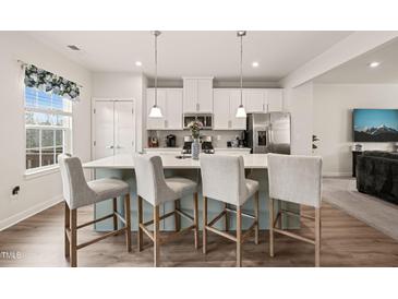 Bright kitchen with stainless steel appliances, white cabinets, and a large center island with bar stool seating at 368 Amber Acorn Ave, Raleigh, NC 27603