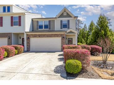 Charming townhome featuring a stone-accented facade, attached garage, and beautifully landscaped front yard with colorful shrubs at 420 Retreat Ln, Wake Forest, NC 27587