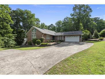 Charming brick home featuring an attached two car garage and a long driveway with lush, mature landscaping at 4905 Will-O-Dean Rd, Raleigh, NC 27616