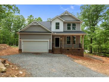 Charming two-story home featuring a covered front porch, two car garage and classic gray siding at 5507 Eagles Nest Trl, Snow Camp, NC 27349