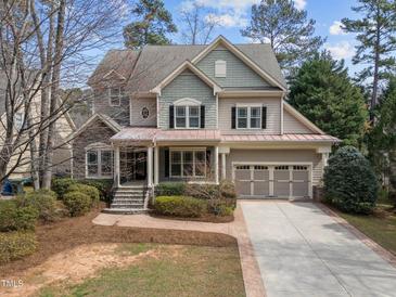 Charming home with a manicured front yard, showcasing its unique architectural details and a three car garage at 5714 Belmont Valley Ct, Raleigh, NC 27612