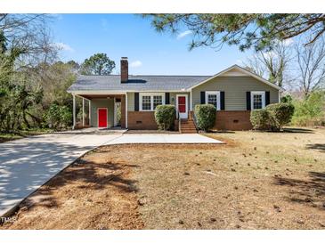 Charming single-story home featuring a red door, brick accents, and a covered carport at 8412 Pierce Olive Rd, Apex, NC 27539