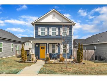 Charming two-story home with blue siding, white trim, a yellow front door, and a well-manicured lawn at 173 E Wilson St, Clayton, NC 27520