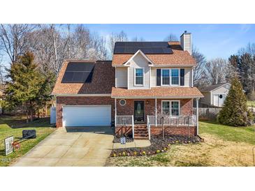 Charming two-story home with brick facade, front porch, solar panels and manicured landscaping at 304 Briarwood Dr, Mebane, NC 27302