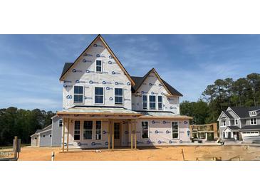 Two-story house under construction featuring a gable roof, multiple windows, and a framed porch, set against a blue sky at 3200 Balcon Ct # 28, Angier, NC 27501