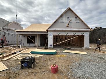 New construction shows the exterior of a house with exposed framing and garage and a cloudy sky at 41 W Emily Gardens Dr, Selma, NC 27576