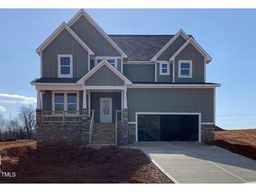 Charming two-story home with stone accents, a covered porch, and an attached two-car garage at 4889 Grosbeak Ct, Mebane, NC 27302