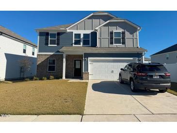 Charming two-story home featuring blue siding, brick accents, and an attached two-car garage at 768 Riguard Way, Wendell, NC 27591