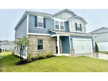 Charming two-story home featuring blue siding, a brick facade, and an attached two-car garage at 768 Riguard Way, Wendell, NC 27591