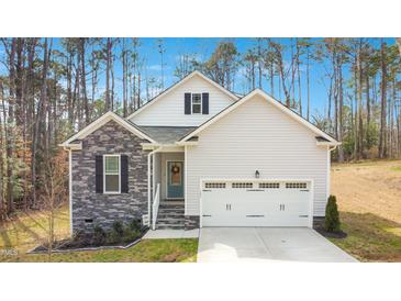 Charming single Gathering home with stone accents, lush landscaping, and an attached two-car garage at 121 Sacred Fire Rd, Louisburg, NC 27549