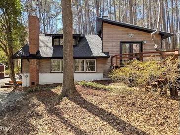 View of the home's exterior, featuring wood siding, a brick chimney, and a sloped roof at 1269 Manns Chapel Rd, Pittsboro, NC 27312