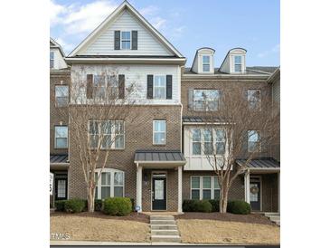 Charming brick townhome featuring black shutters, a covered entry, and manicured landscaping at 1319 Rodessa Run, Raleigh, NC 27607