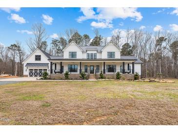 Stunning two-story white farmhouse with a welcoming front porch and well-manicured lawn at 2418 Crossroads Ave, Hillsborough, NC 27278