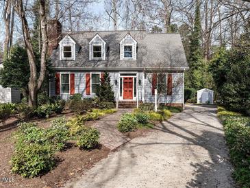 Charming Cape Cod home with dormer windows, red shutters, brick chimney, and lush landscaping at 2512 Winterbury Ct, Raleigh, NC 27607