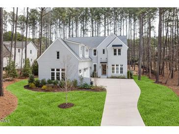 A charming, two-story grey home features a manicured lawn and a long driveway at 49 Bonterra Way, Chapel Hill, NC 27516
