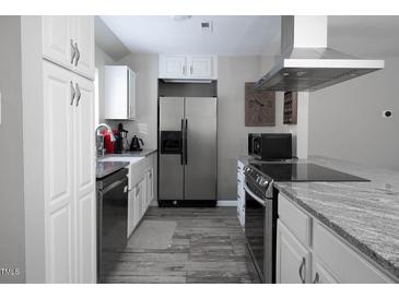 Well-lit kitchen with stainless steel appliances, granite countertops, and white cabinets at 543 Pine Ridge Place, Raleigh, NC 27609