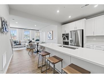 Modern kitchen featuring white cabinets, stainless steel appliances, and a spacious island with seating at 600 Hedrick Ridge Road # 104, Cary, NC 27519