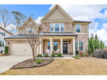 Inviting two-story home with a stone facade, manicured lawn, and a charming front porch at 156 Greenhurst Cir, Holly Springs, NC 27540