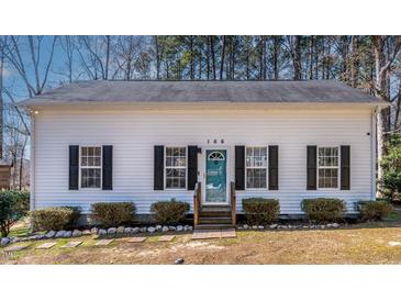 Charming single-story home with a blue door, black shutters, and a well-manicured front yard at 166 Creek Dr, Louisburg, NC 27549