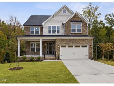 Beautiful two-story home featuring a stone facade, inviting front porch, and a two-car garage at 3154 Armeria Dr, Apex, NC 27502