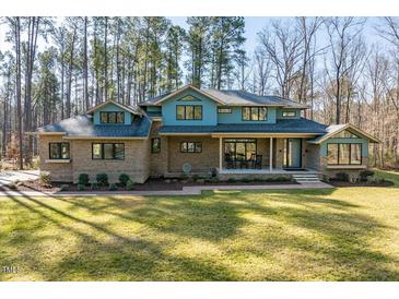 Two-story brick home with a blue accent wall, inviting front porch and a manicured lawn at 38 Kingbird Ln, Chapel Hill, NC 27517