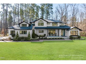 Stunning two-story home boasts a white painted brick exterior, black accents, and a lush green lawn at 38 Kingbird Ln, Chapel Hill, NC 27517