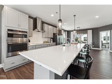 Modern kitchen with stainless steel appliances, gray cabinets, white countertops and island with bar stool seating at 600 Hedrick Ridge Road # 306, Cary, NC 27519