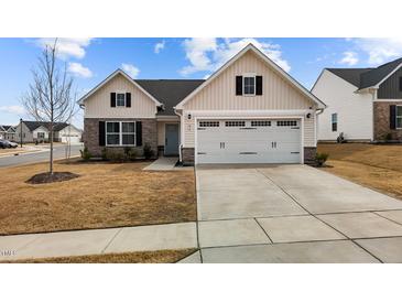 Charming one-story home with a two-car garage and a combination of stone and vertical siding at 82 Coble Farms Pl, Fuquay Varina, NC 27526