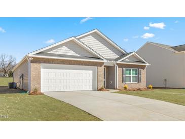 Charming single-story home featuring a brick facade, two-car garage, and neatly manicured lawn on a sunny day at 880 Forth Ct, Gibsonville, NC 27249