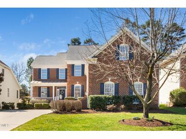 Charming two-story brick home with blue shutters, well-manicured lawn, and inviting front porch at 9344 Palm Bay Cir, Raleigh, NC 27617