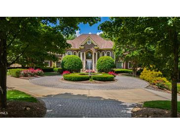 Stately brick home featuring a circular driveway with fountain and manicured landscaping at 2421 Acanthus Dr, Wake Forest, NC 27587