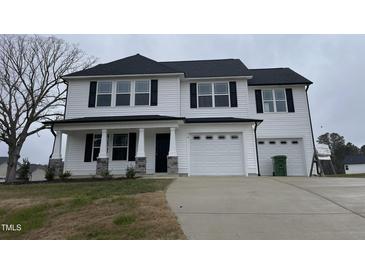 Charming two-story home featuring a two-car garage and a covered front porch at 76 Mangrove Ct, Four Oaks, NC 27524