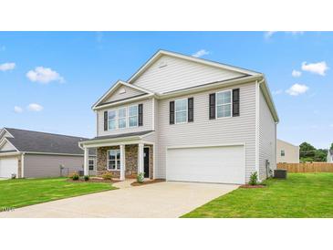 Charming two-story home with a manicured lawn and a two-car garage at 857 Forth Ct, Gibsonville, NC 27249