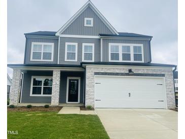 Charming two-story home with gray siding, stone accents, a two-car garage and a well-manicured lawn at 130 W Crescent Mills Blvd # Homesite 251, Wilson's Mills, NC 27520