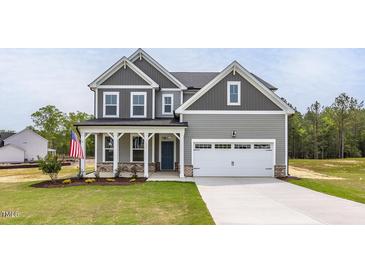 Charming two-story home with gray siding, white trim, covered porch, landscaped yard and two car garage at 173 Wild Turkey Way, Lillington, NC 27546