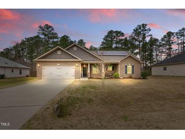 Charming brick home with a two-car garage, manicured lawn and beautiful landscaping at 38 Parkside Dr, Lillington, NC 27546