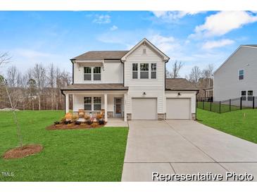 Charming two-story home featuring a well-manicured lawn, a two-car garage, and a welcoming front porch at 7230 Tillage Rd # 84 Triad, Mebane, NC 27302