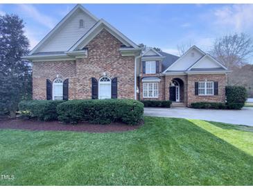 Charming brick home featuring black shutters, arched windows, a well-manicured lawn, and a circular driveway at 138 Parkdale Ln, Clayton, NC 27520