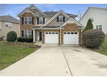 Charming two-story home featuring a stone facade, two-car garage, and well-manicured lawn at 1756 Main Divide Dr, Wake Forest, NC 27587