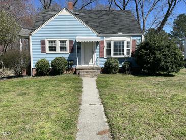 Charming blue home featuring a well-manicured lawn and inviting front entrance at 214 Grace St, Oxford, NC 27565